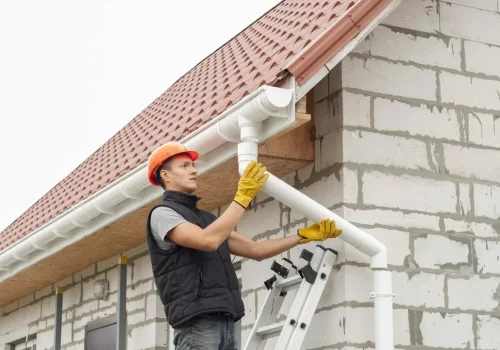 Gutter installation worker securing a white gutter system Gutter installation worker securing a white gutter system