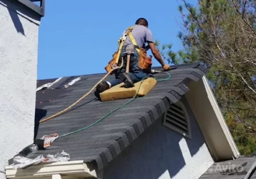 Roofer installing shingles on a sloped residential roof Roofer installing shingles on a sloped residential roof