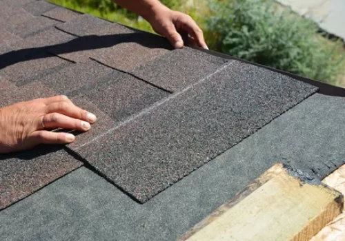 Close up of hands checking asphalt roof shingles Close up of hands checking asphalt roof shingles