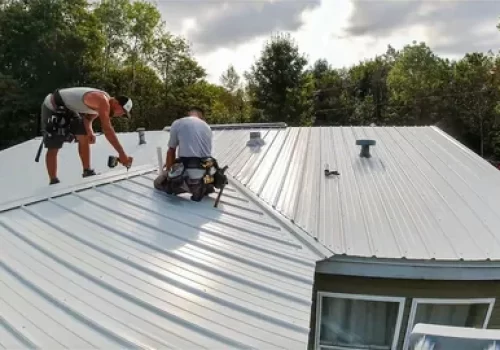 Roofing crew working on a white metal roof Roofing crew working on a white metal roof